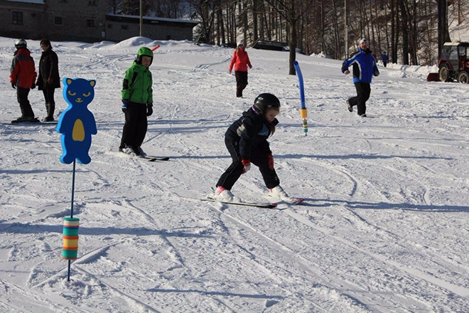 Dětský lyžař učící se lyžovat ve ski areálu Opálená
