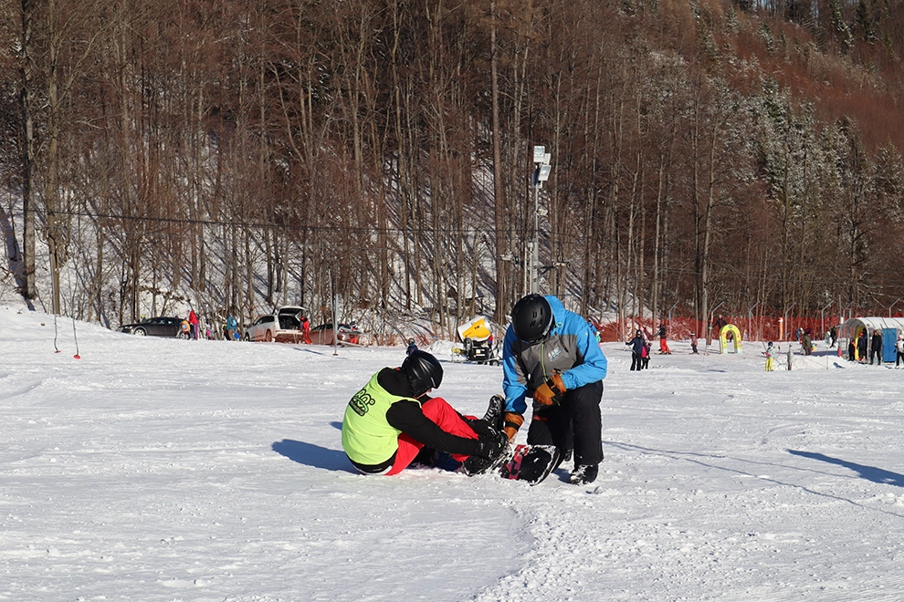 Instruktor v lyžařské škole pomáhá chlapci se snowboardem na sjezdovce Opálené
